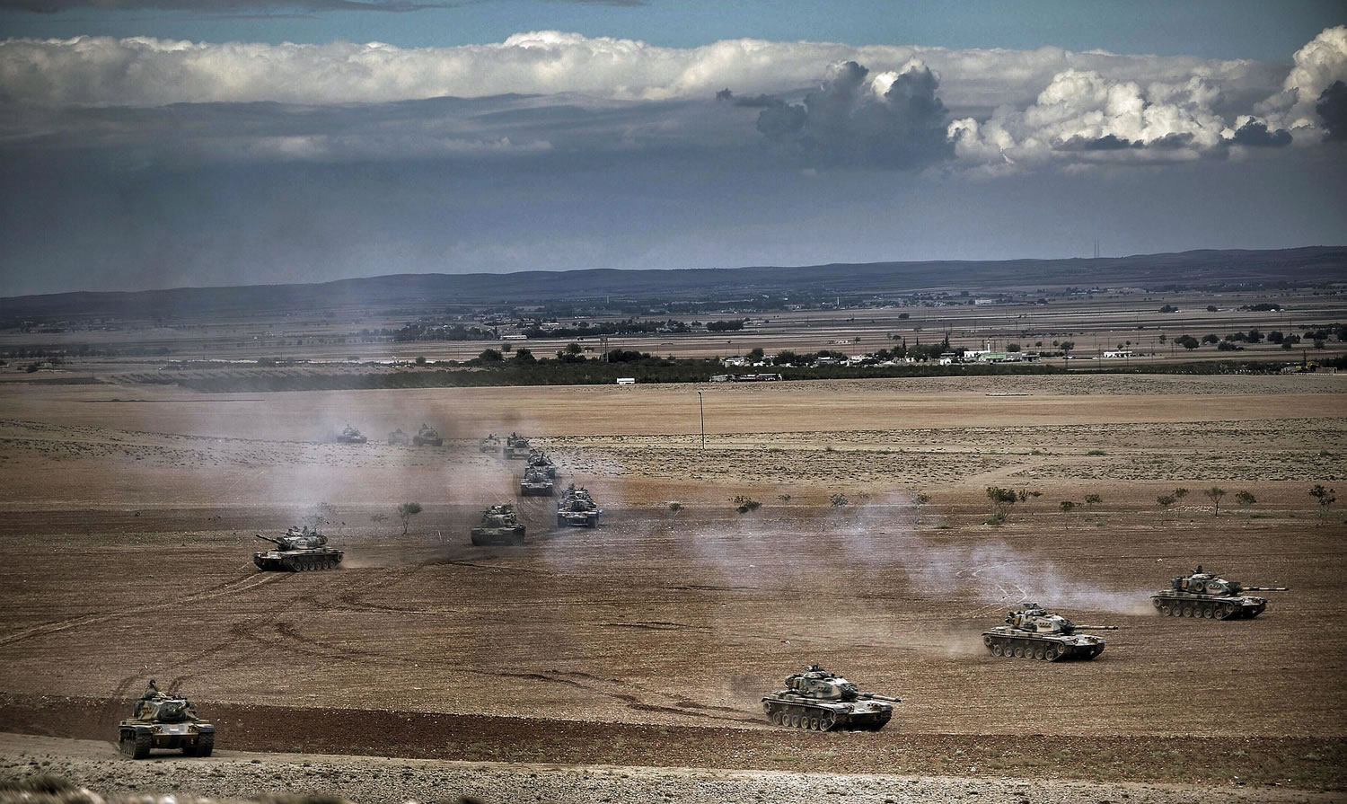 Turkish tanks roll to take positions along the Turkey-Syria border near Suruc, Turkey, on Monday.