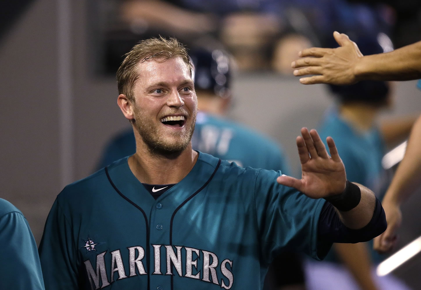 Seattle Mariners' Michael Saunders smiles as he is congratulated in the dugout on his home run against the Minnesota Twins in the seventh inning  Monday in Seattle.