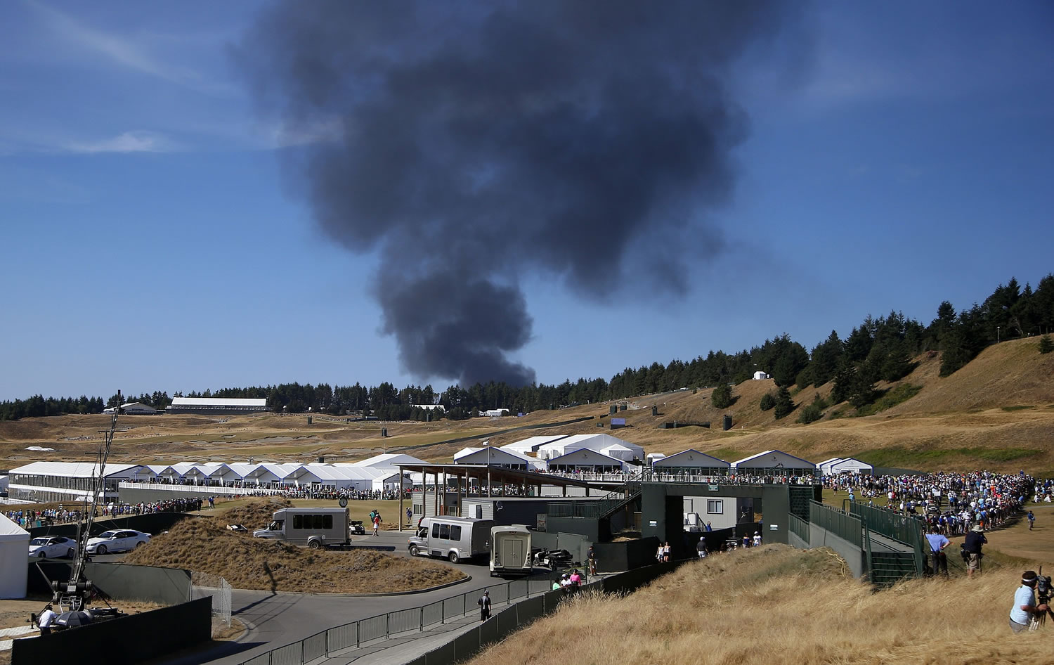 Smoke from a structure fire a few miles from the golf course rises during the third round of the U.S. Open at Chambers Bay on Saturday in University Place. The fire at a marine repair facility was contained within an hour.