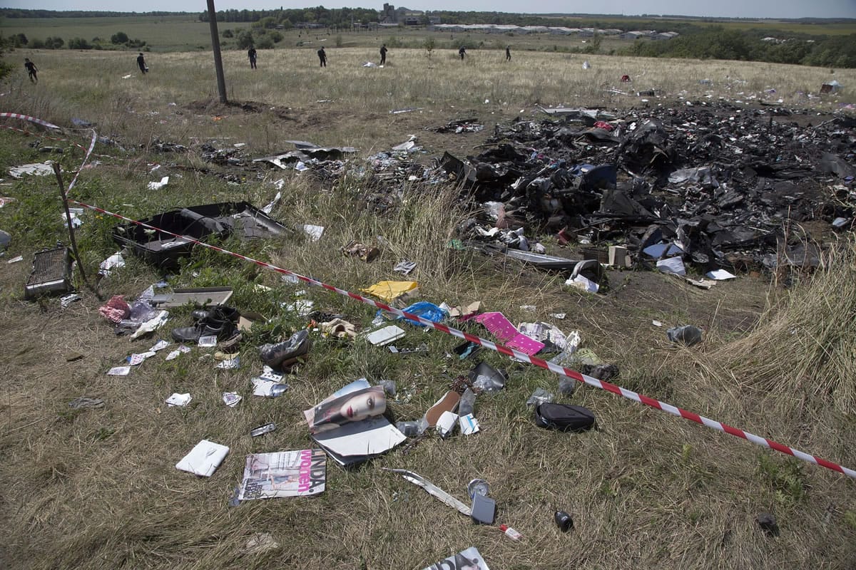 Australian experts in the background,  examine the area of the Malaysia Airlines Flight 17 plane crash, near the village of Hrabove, Donetsk region, eastern Ukraine Friday, Aug. 1, 2014. The investigators from the Netherlands and Australia plus officials with the Organization for Security and Cooperation in Europe traveled from the rebel-held city of Donetsk in 15 cars and a bus to the crash site outside the village of Hrabove. Then they started setting up a base to work from at a chicken farm. The investigative team's top priority is to recover human remains that have been rotting in midsummer heat of 90 degrees (32 degrees Celsius) since the plane went down on July 17.
