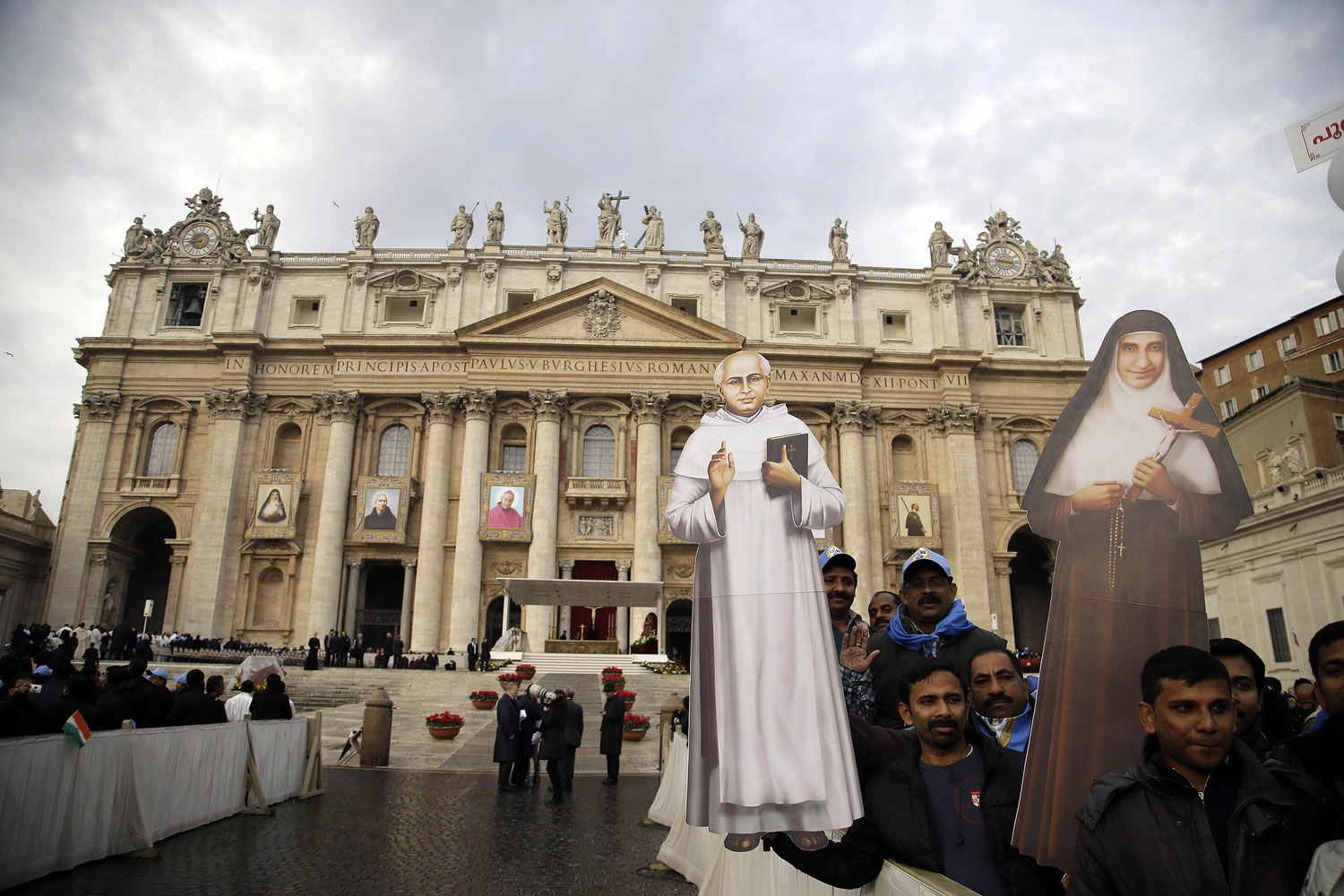 Crowd members hold cardboard cutouts of priest Kuriakose Elias Chavara, left, and sister Eufrasia Eluvathingal in front of St. Peter's Basilica on Sunday prior to the start of their Canonization Mass celebrated by Pope Francis in St.