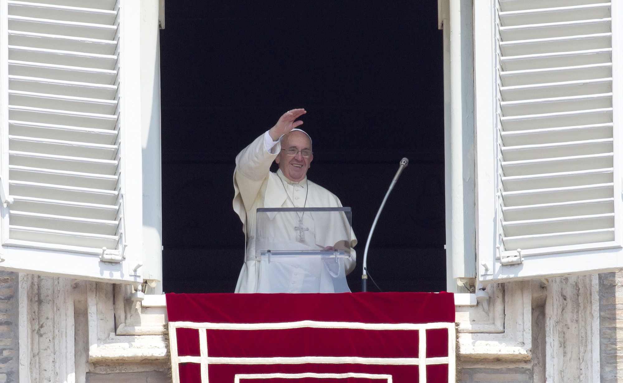 Pope Francis waves to the faithful as he arrives to recite the Angelus noon prayer from his studio window overlooking St.