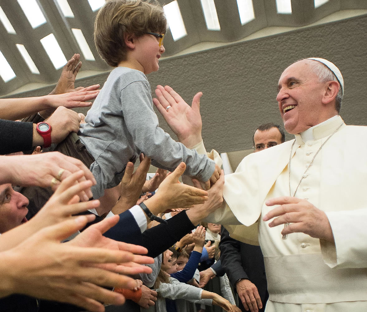 L'Osservatore Romano
Pope Francis greets a child Thursday at an audience with members of Pauline family in the Paul VI hall at the Vatican. The pope will be in the U.S. in September.
