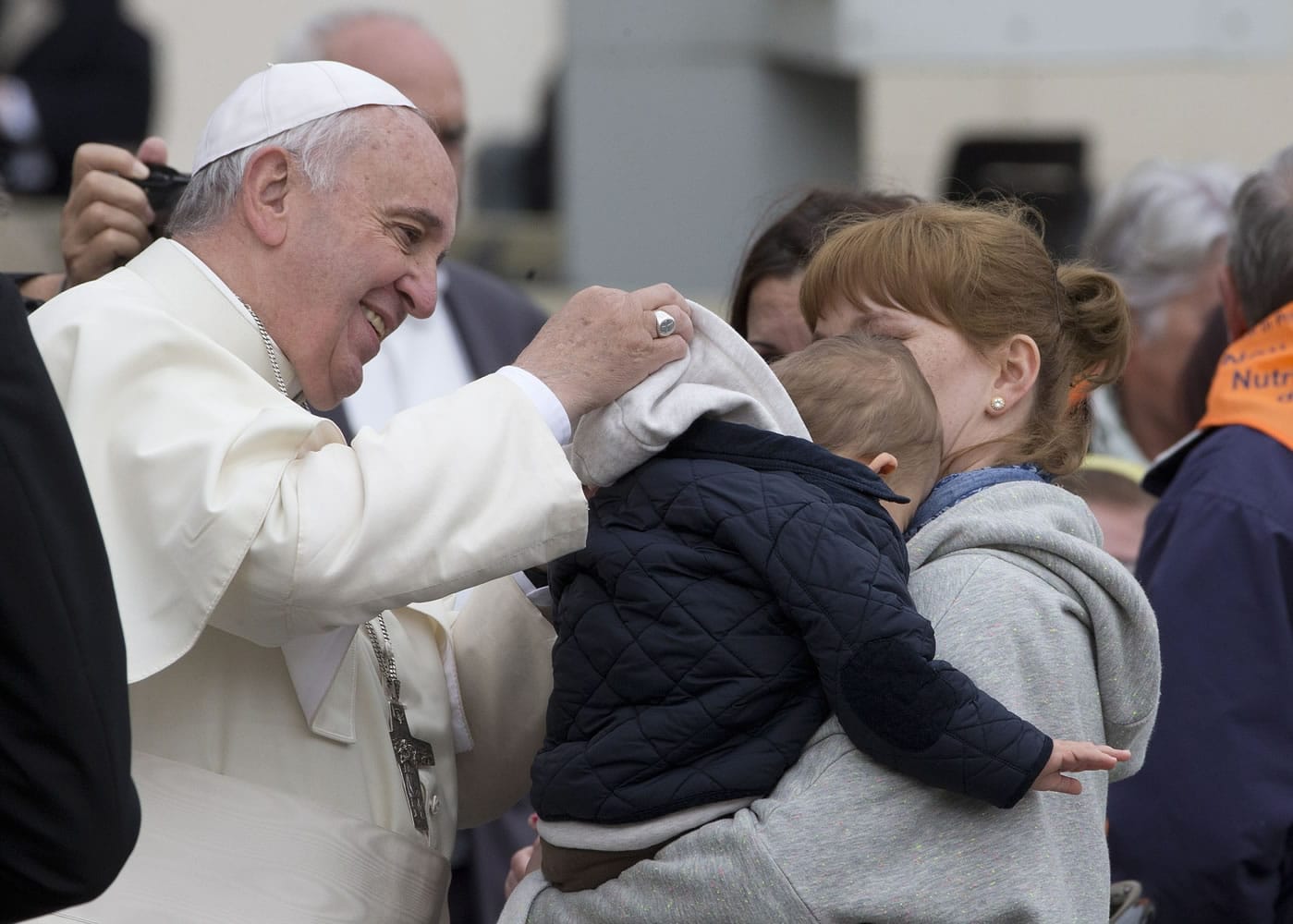 Pope Francis helps a child with a hood Wednesday as he leaves after his weekly general audience in St.