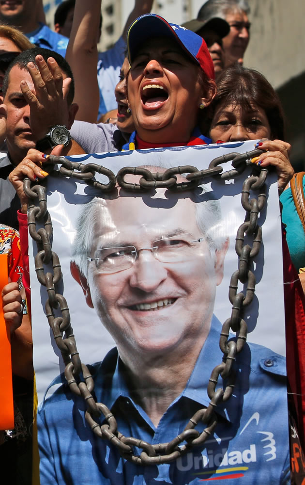 A supporter of Caracas Mayor Antonio Ledezma holds a poster of him with chains during a protest in Caracas, Venezuela, Friday, Feb. 20, 2015. Demonstrators are condemning last night's surprise arrest of Ledezma for allegedly plotting to overthrow the government of President Nicolas Maduro. Late Thursday Maduro said that Ledezma, one of the most vocal opposition leaders, would be punished for trying to sow unrest in Venezuela.