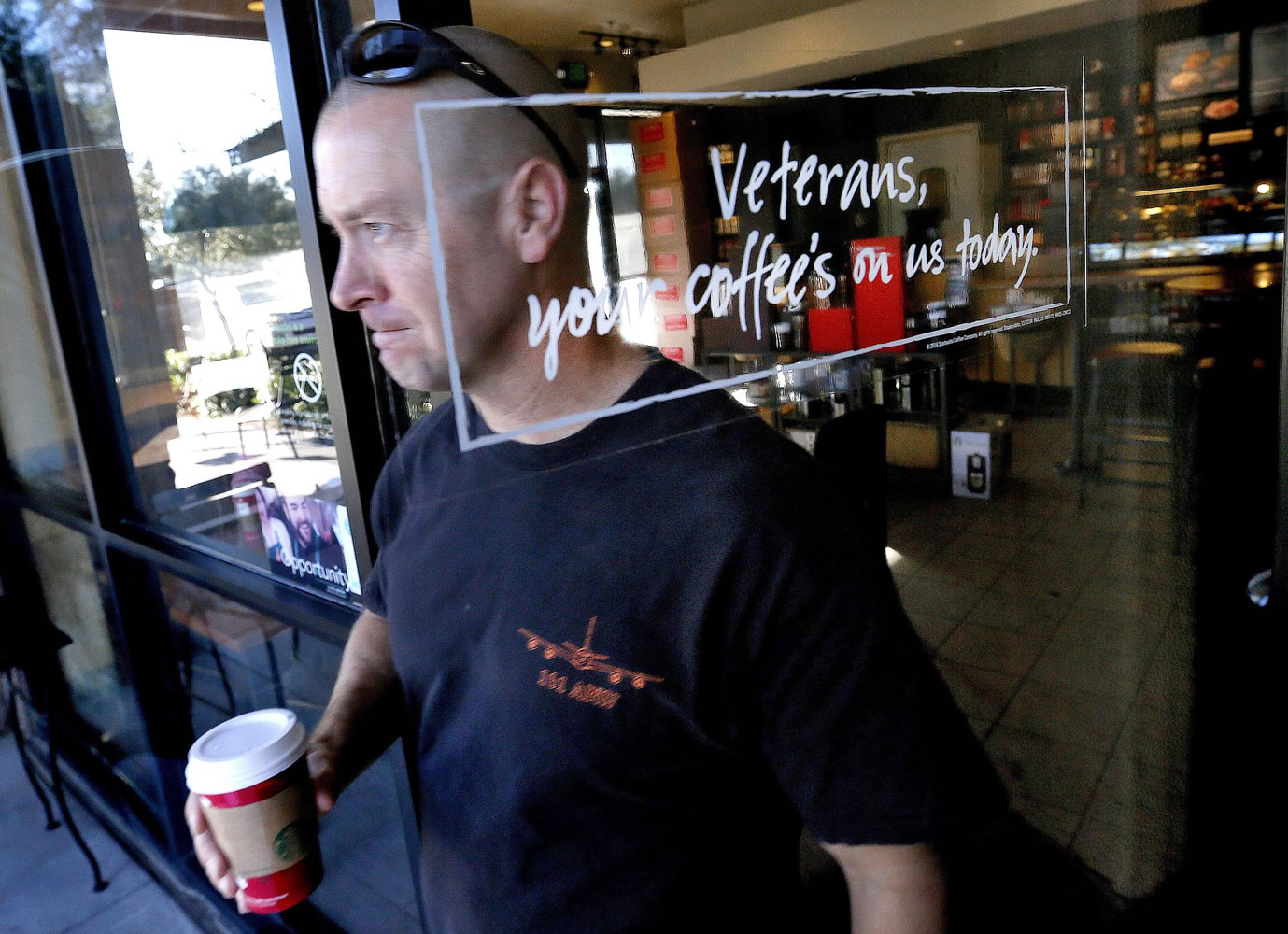 Arizona Air National Guard Lt. Col. Greg Grattop, 161st Air Refueling Wing, Phoenix Sky Harbor and Operation Enduring Freedom veteran who has served in Afghanistan, exits a Starbucks with his free coffee Tuesday in Chandler, Ariz. Starbucks is giving away free coffee to military veterans on Veteran's Day. Lt.