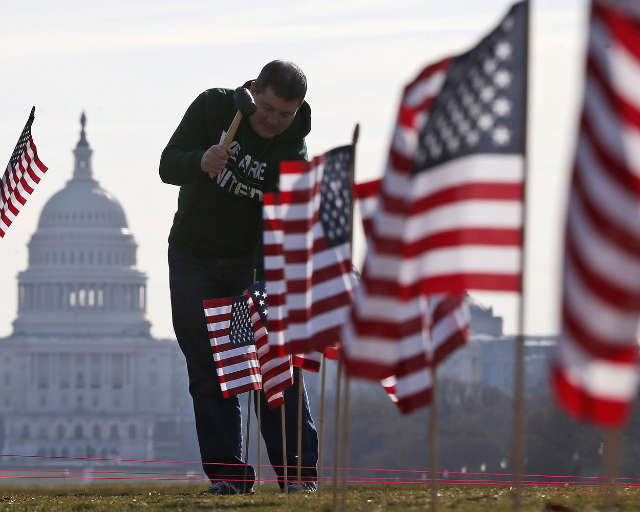 With the Capitol in the background, Army veteran David Dickerson of Oklahoma City, Okla., joins others to place 1,892 flags representing veteran and service members who have died by suicide to date in 2014, on the National Mall in Washington.