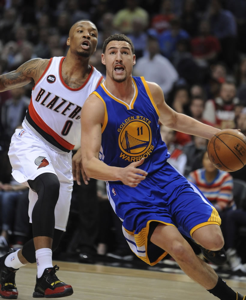 Golden State Warriors' Klay Thompson (11) drives against Portland Trail Blazers' Damian Lillard (0) during the first half of an NBA basketball game in Portland, Ore., Tuesday, March 24, 2015.