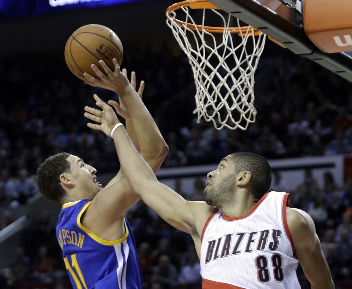 Golden State Warriors guard Klay Thompson, left, goes to the hoop against Portland Trail Blazers forward Nicolas Batum during the first half in Portland, Ore., Sunday, Nov. 2, 2014.