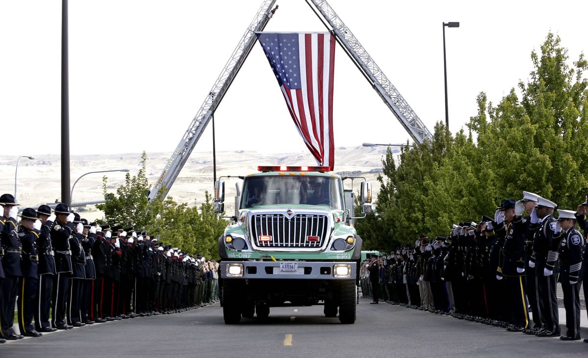 A U.S. Forest Service truck passes as firefighters salute the arrival of a motorcade for a memorial service for three firefighters killed in a wildfire, Sunday, Aug. 30, 2015, in Wenatchee, Wash. Richard Wheeler, Andrew Zajac and Thomas Zbyszewski died Aug. 19 in a fire near Twisp, Wash.