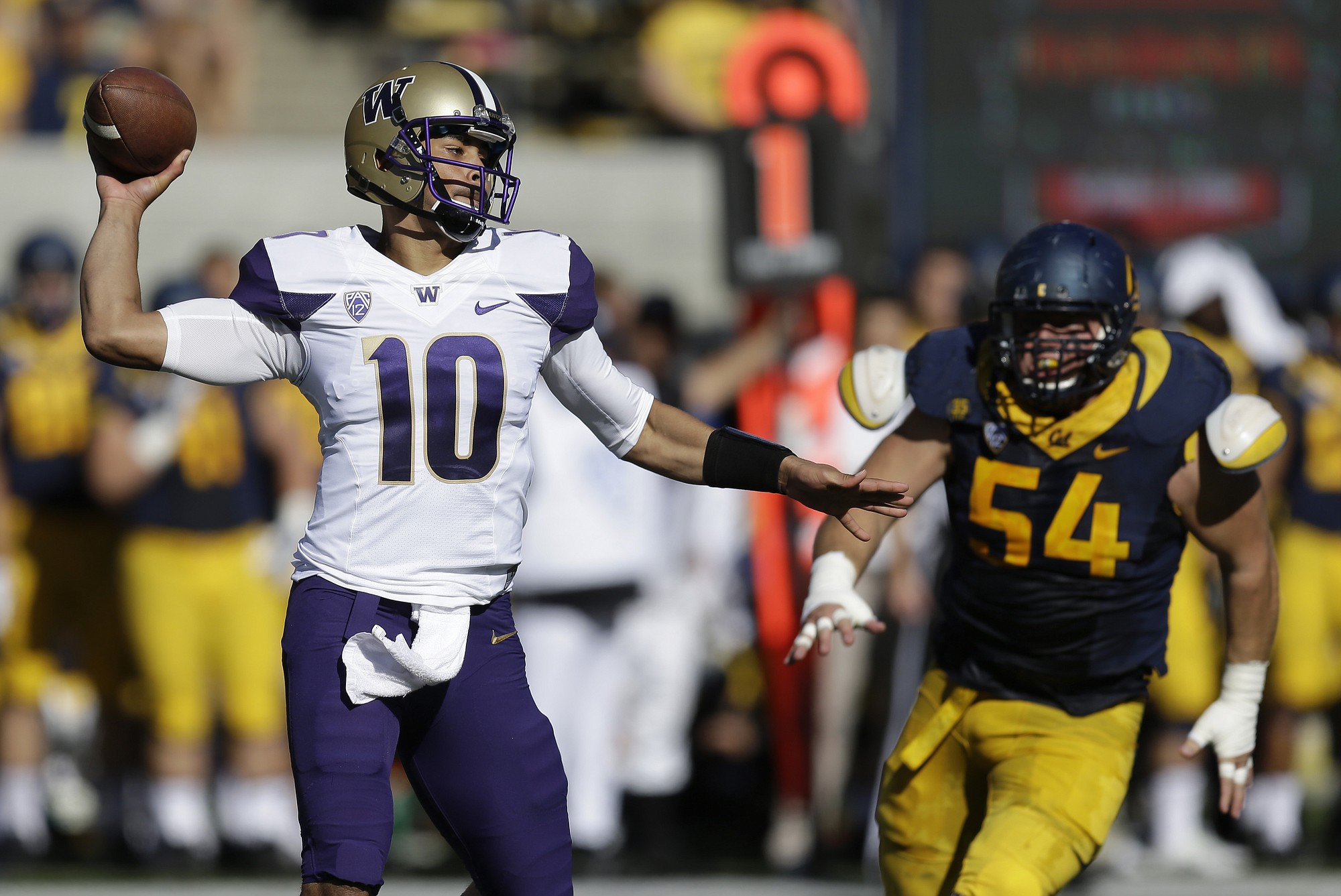 Washington quarterback Cyler Miles, left, passes under pressure from California's Austin Clark during the first half of an NCAA college football game Saturday, Oct. 11, 2014, in Berkeley, Calif.