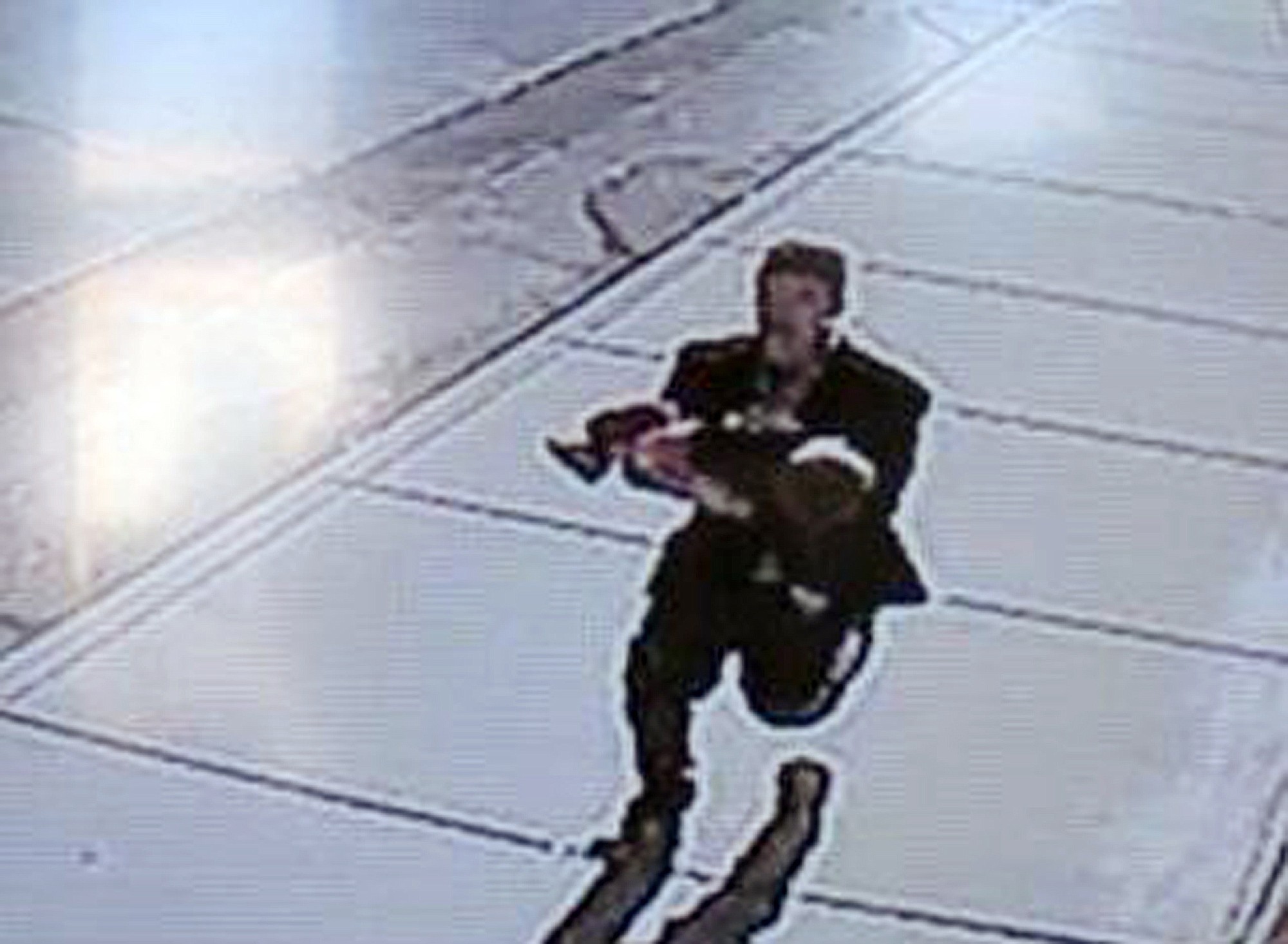 In this image taken from surveillance video on March 8, a man runs down a street, carrying a toddler in an apparent kidnapping attempt in Sprague.