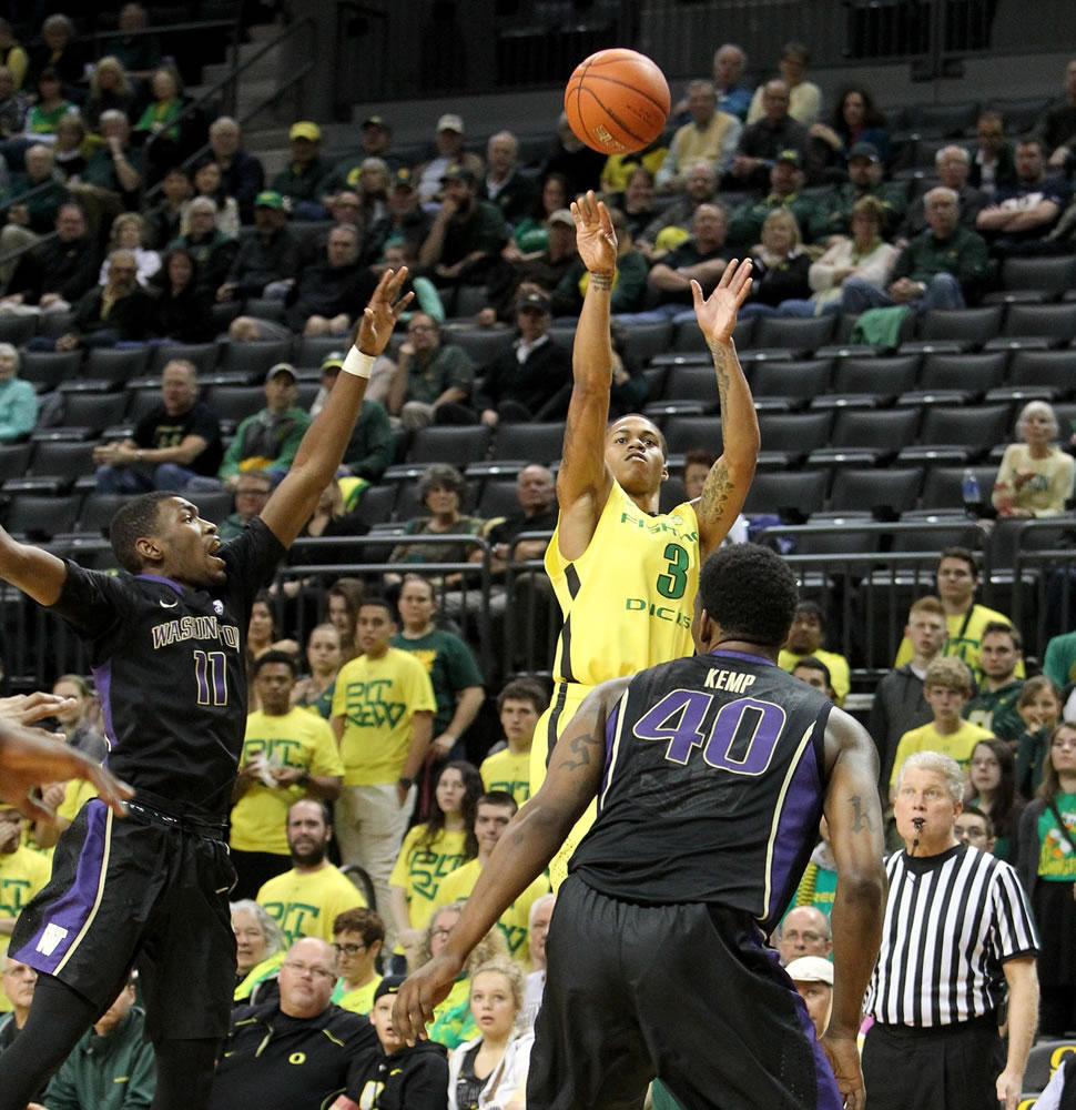 Oregon's Joseph Young, right, shoots a 3-point shot over Washington's Mike Anderson, left, and Shawn Kemp Jr., right, during the first half on Wednesday, Feb. 4, 2015.