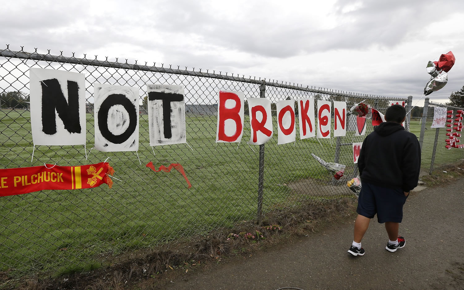 Part of a sign that reads &quot;Cracked But Not Broken,&quot; is shown Monday at a growing memorial on a fence around Marysville Pilchuck High School in Marysville.