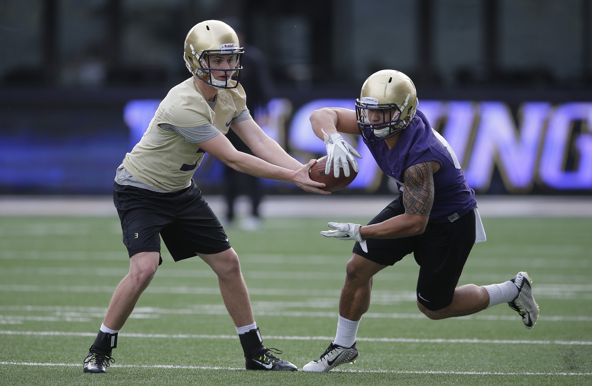 Washington quarterback Jake Browning, left, hands off to tailback Ralph Kinne, right, during spring football practice, Monday, March 30, 2015, in Seattle. (AP Photo/Ted S.