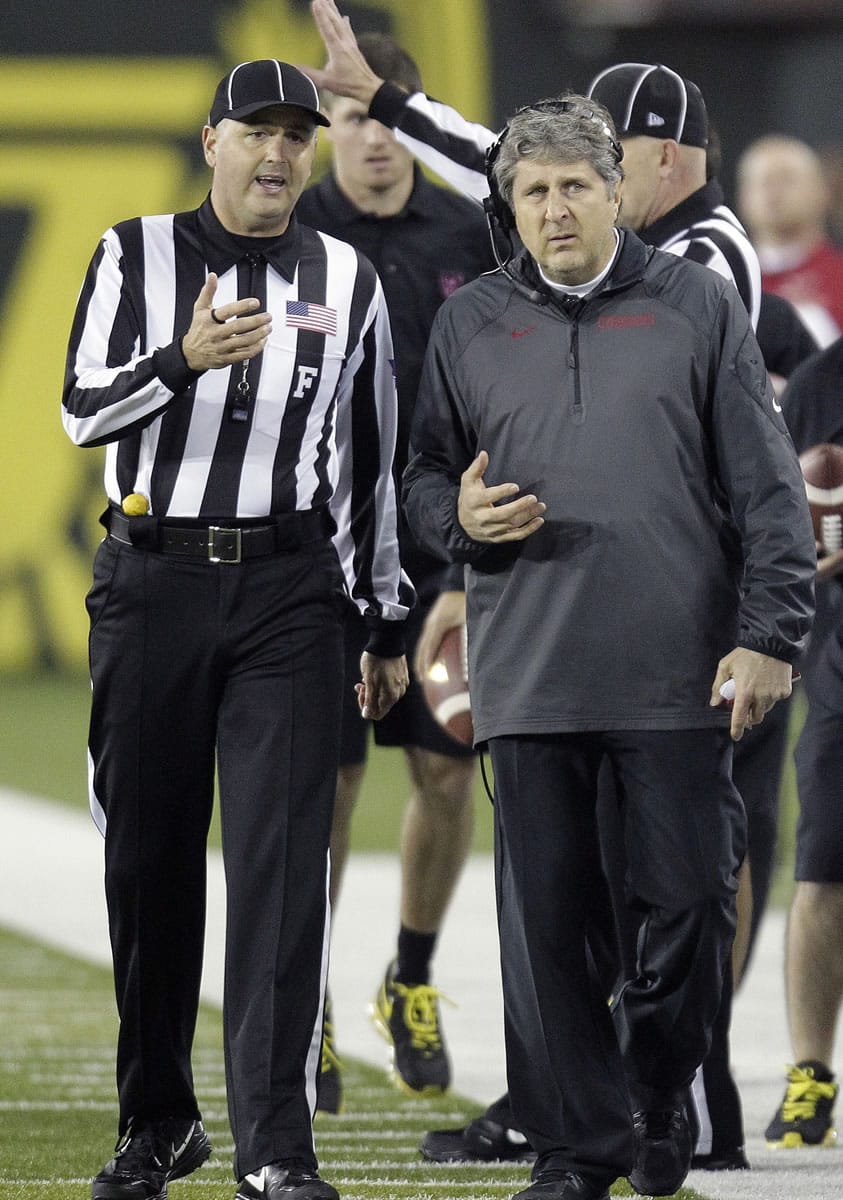 Washington State coach Mike Leach, right, questions a call with a referee during the second half of an NCAA college football game against Oregon in Eugene, Ore., Saturday, Oct. 19, 2013. Oregon won 62-38.