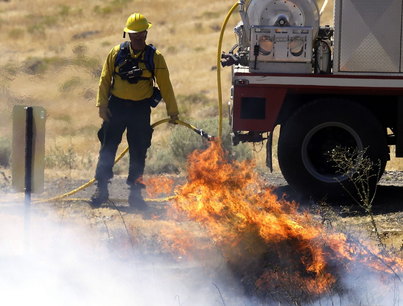 A firefighter keeps an eye on a blaze as small spot fires are allowed to burn out around Roosevelt on Aug.