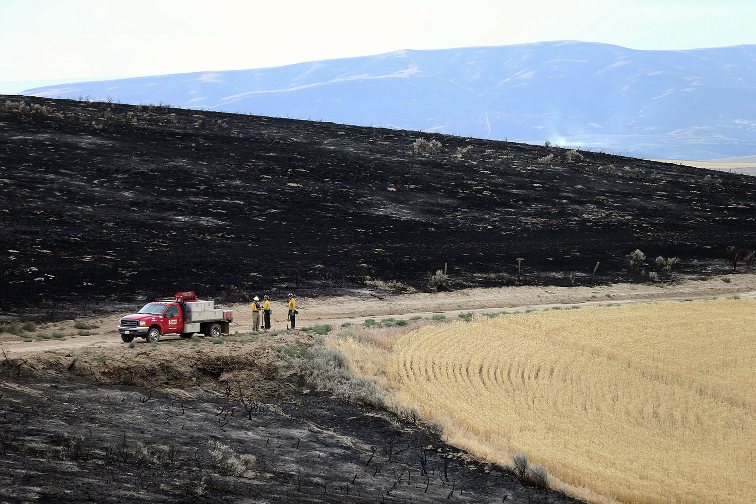 Three Chewack Fire Suppression workers stand Sunday near ground burned by the Douglas County Complex Fire near Waterville.
