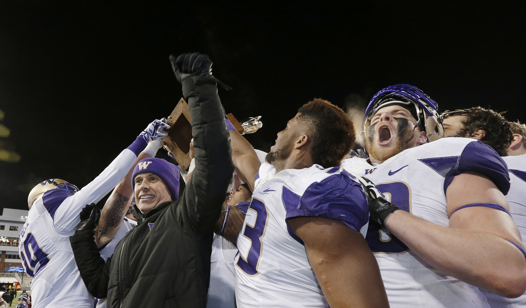 Washington coach Chris Petersen, left, celebrates with players Saturday, Nov. 29, 2014, in Pullman, after Washington defeated Washington State 31-13 in the Apple Cup. (AP Photo/Ted S.