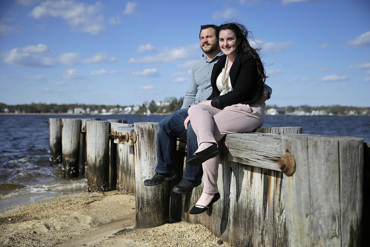 Kate MacHugh and fiance CJ Ecke sit together on a seawall in Pine Beach, N.J. The couple is getting hitched Oct.