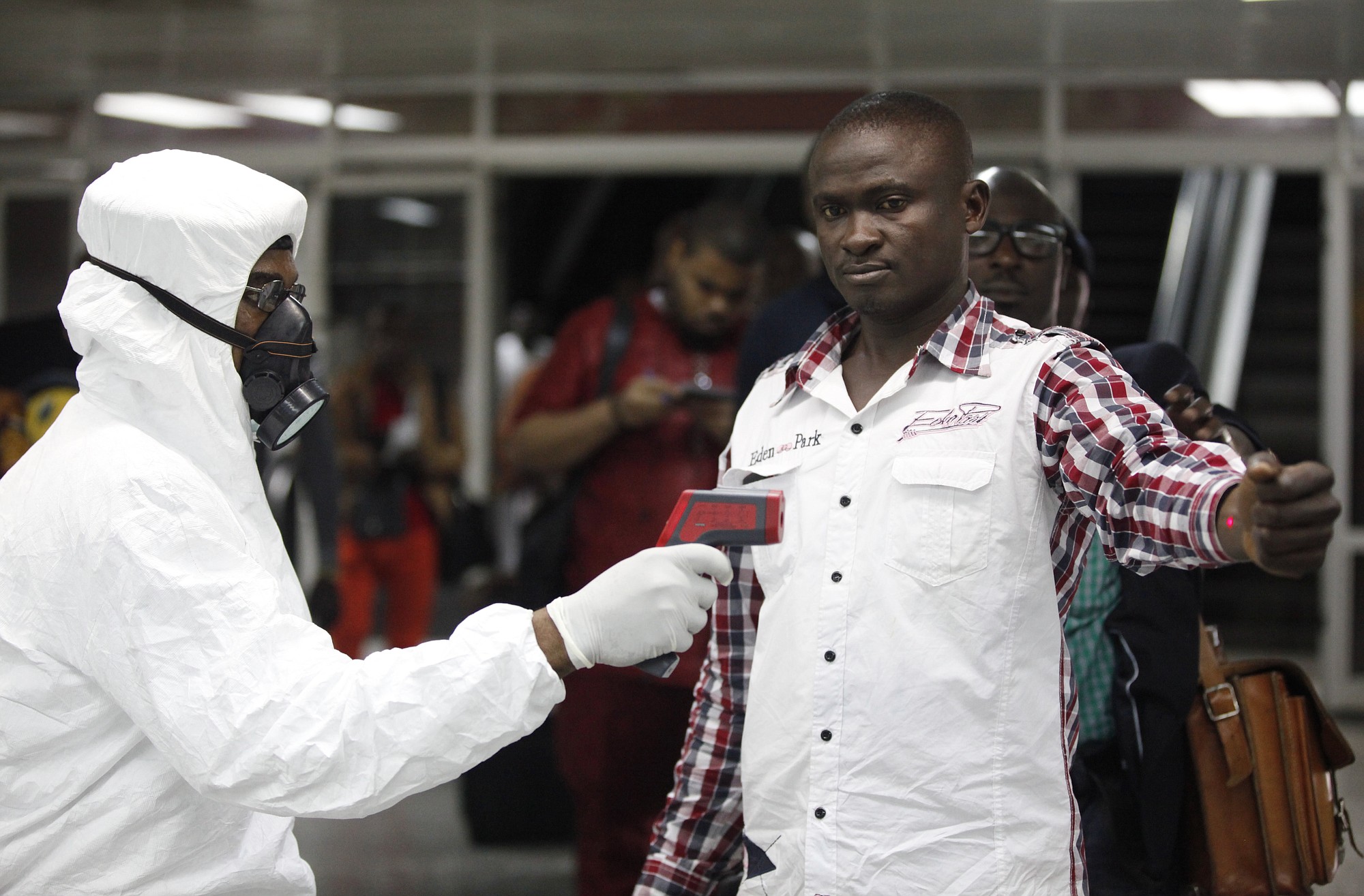 A port health official uses a thermometer to screen a worker Wednesday at Murtala Muhammed International Airport in Lagos, Nigeria.