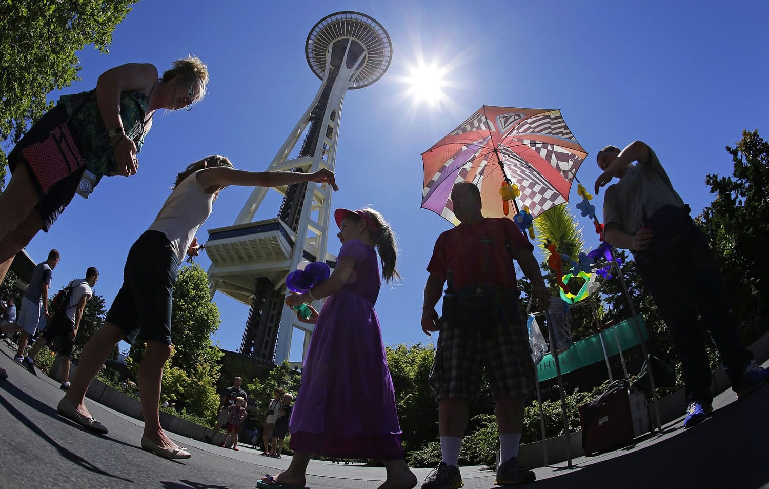 Kevin Pinnell, second from right, shows Wednesday that people in Seattle don't just need umbrellas during the rainy season as he stands under his for shade from the sun.