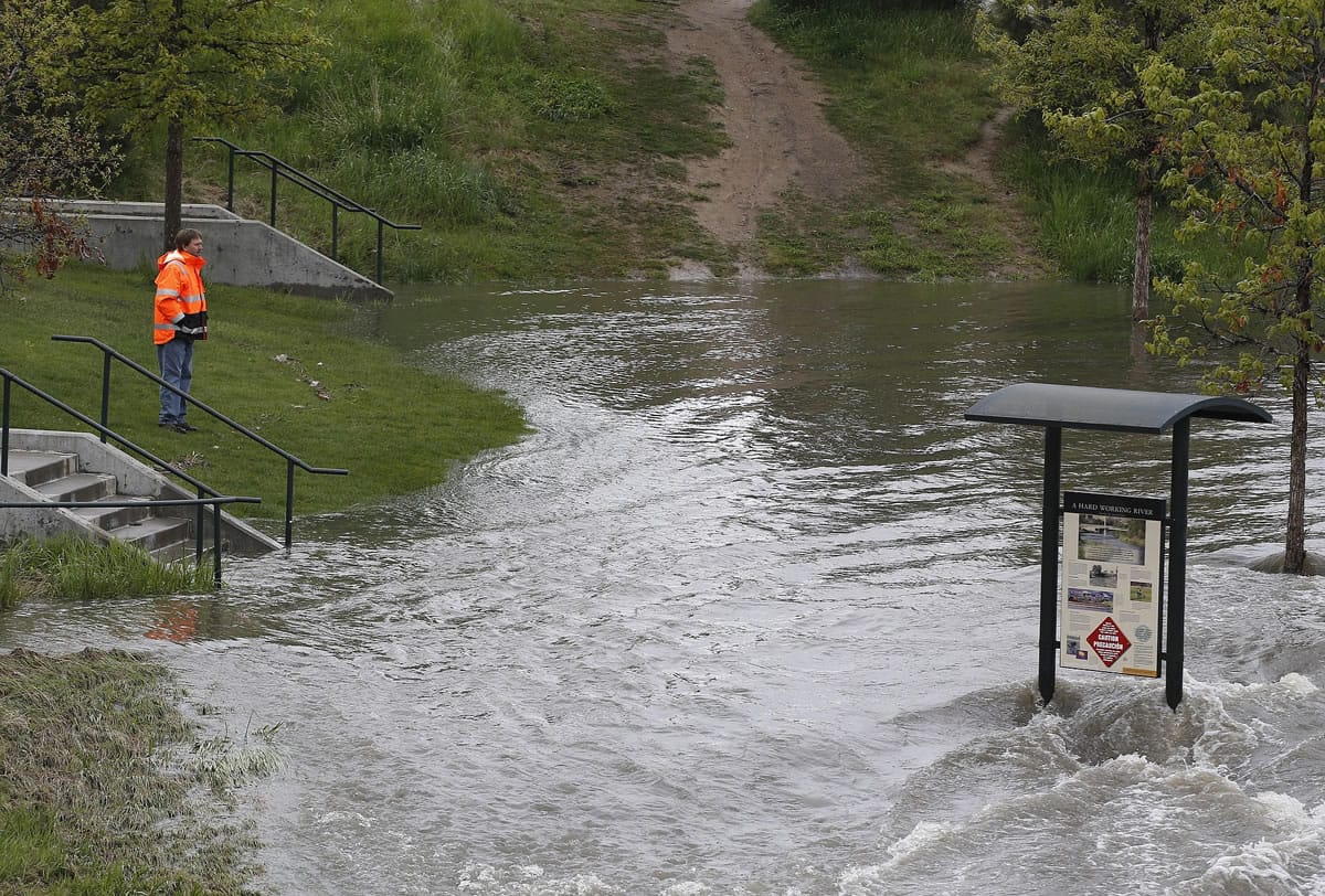 A man looks out at a riverside park flooded from heavy rain in Denver, Colo., Tuesday, May 19, 2015. Colorado braced for a spring storm with unseasonably heavy rains and snow expected in the high country.