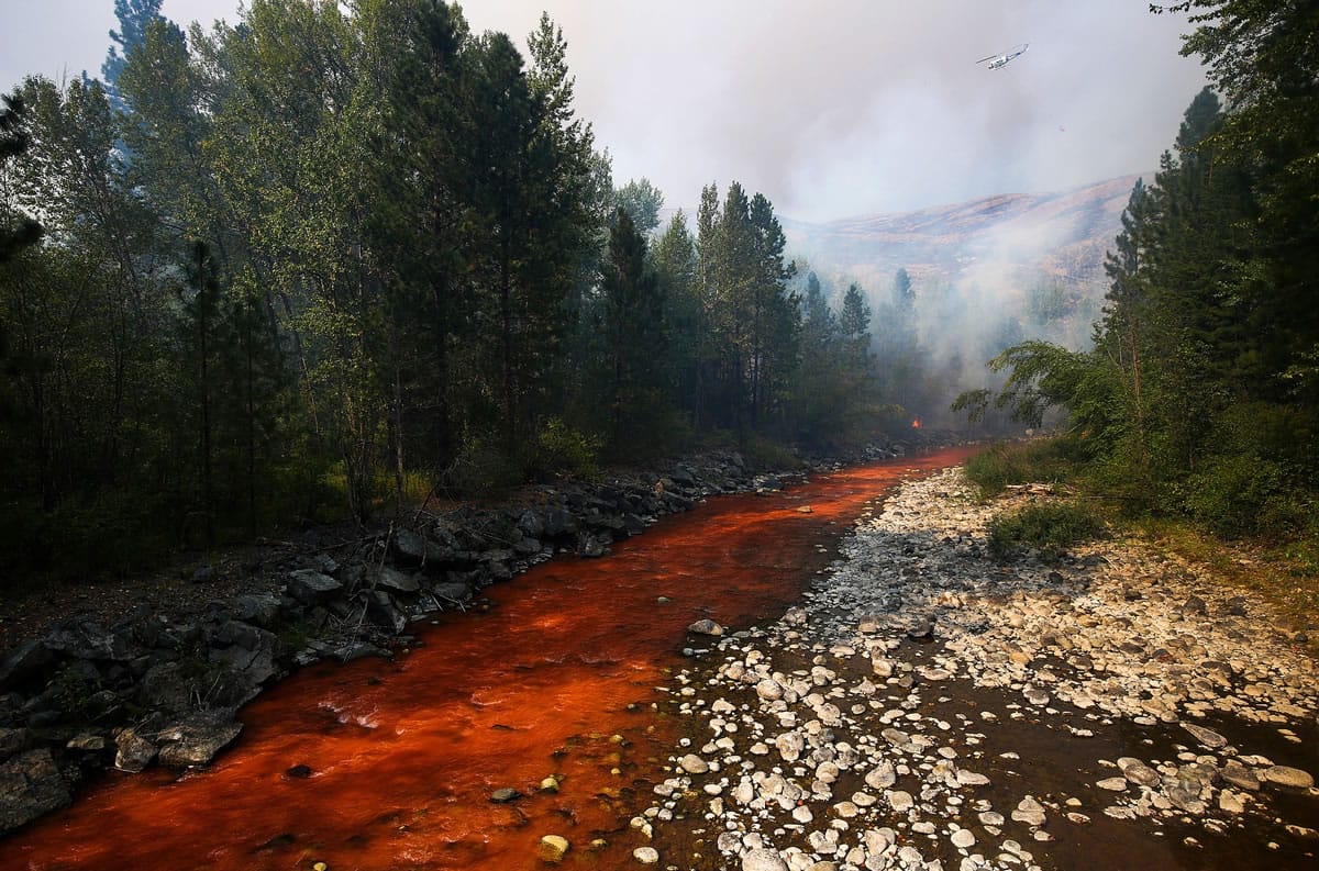 The Twisp River is turned a deep red after an aerial drop of fire retardant landed in the river Thursday as a fire flared up near Twisp.