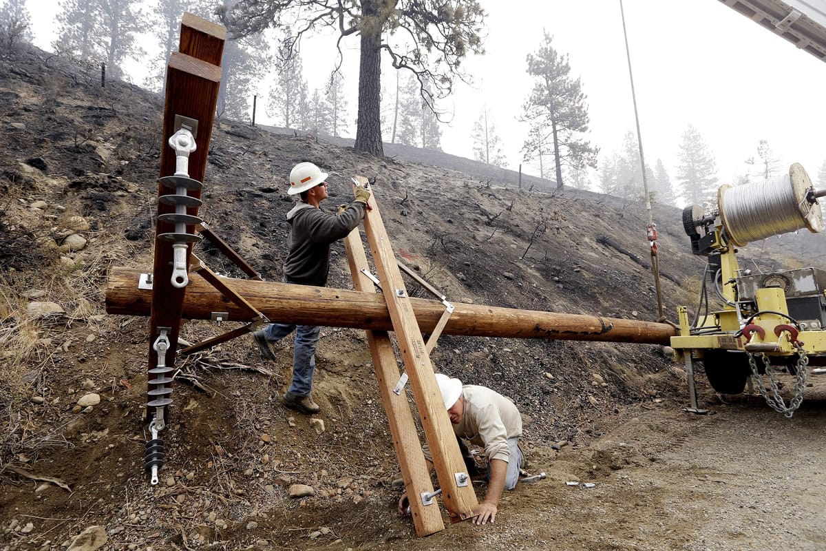 Utility workers Chris Zahn, left, and Dan Foussard work to install a new pole Sunday to replace one of about 50 that burned along Twisp River Road in a wildfire days earlier.Reduced winds on Saturday helped firefighters gain the upper hand against the series of giant wildfires in north-central Washington.