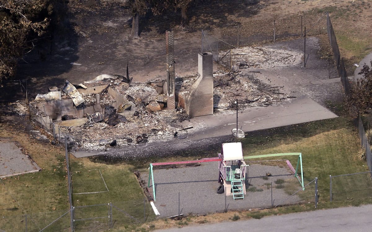 A play structure remains Thursday near a house lost to wildfire days earlier near Chelan.