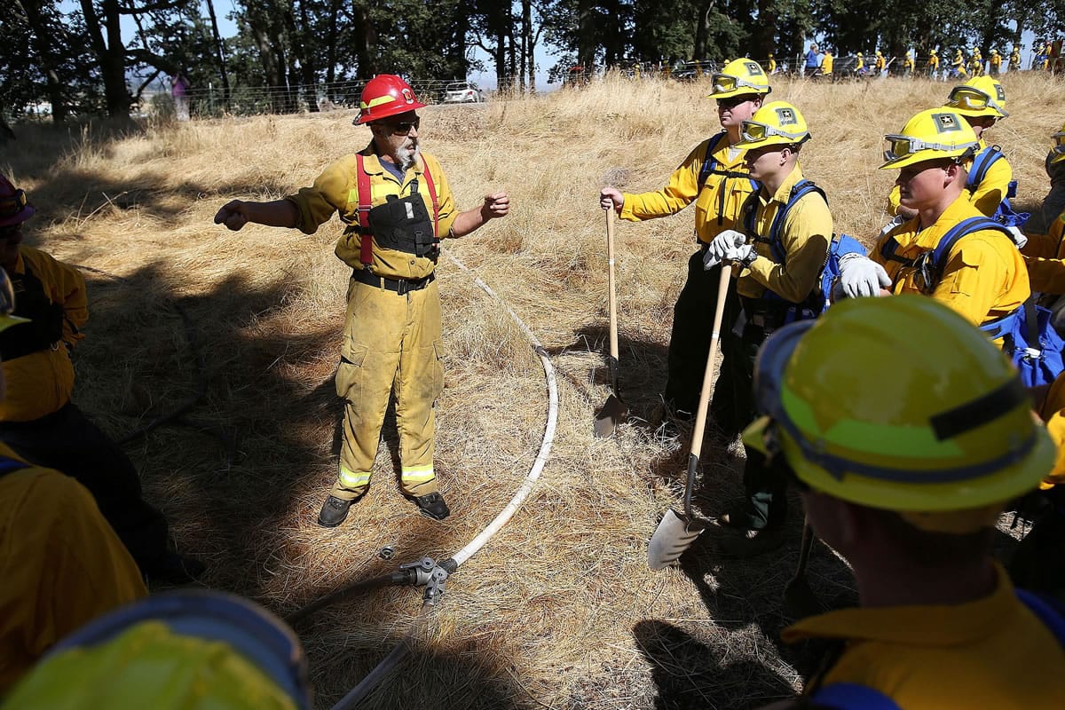 Don Willis, with the Sun River Fire Department, talks with members of the Oregon National Guard during wildland fire training Tuesday in Salem, Ore.
