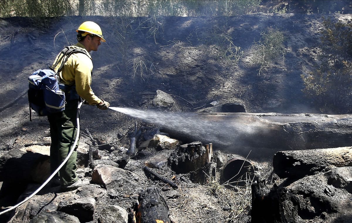Firefighter Kevin Cason waters down a hot spot while working on the Kyburz fire near Kyburz, Calif., on Friday.