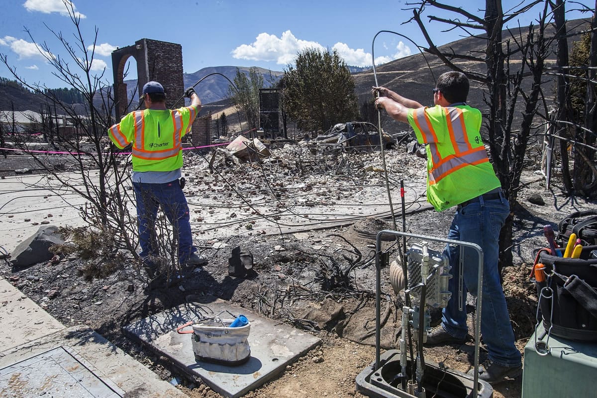 A utility crew sets out to replace the cable that was destroyed inside the Broadview neighborhood by this weekend's fire in Wenatchee on Tuesday.