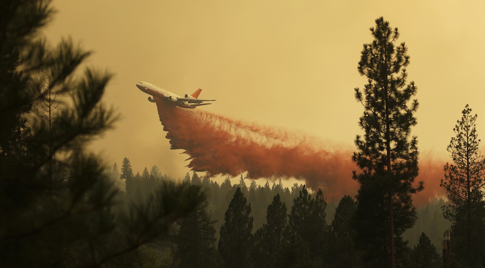 An airplane tanker flies through smoky air as it drops fire retardant on a wildfire that flared up in the late afternoon Thursday near Omak.