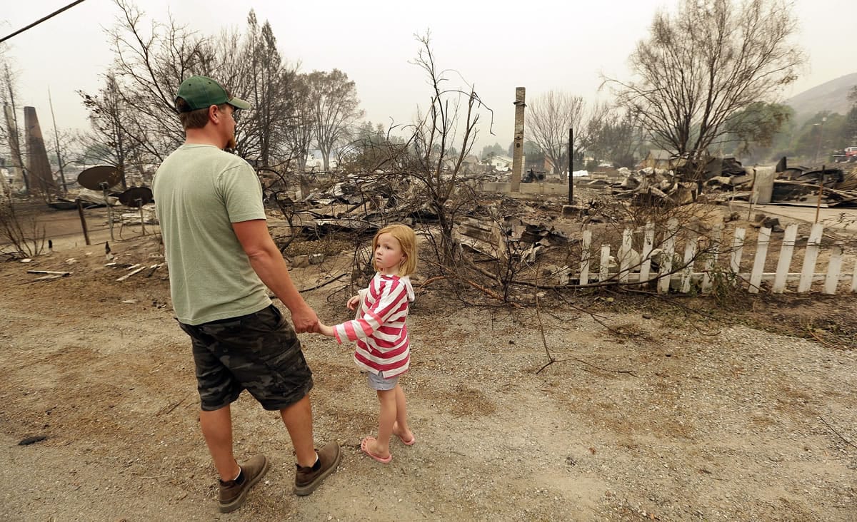 Forrest Harrison holds the hand of his daughter, Avery, 5, as he looks over the rubble of his home in Pateros on Friday after a wildfire destroyed it the night before.