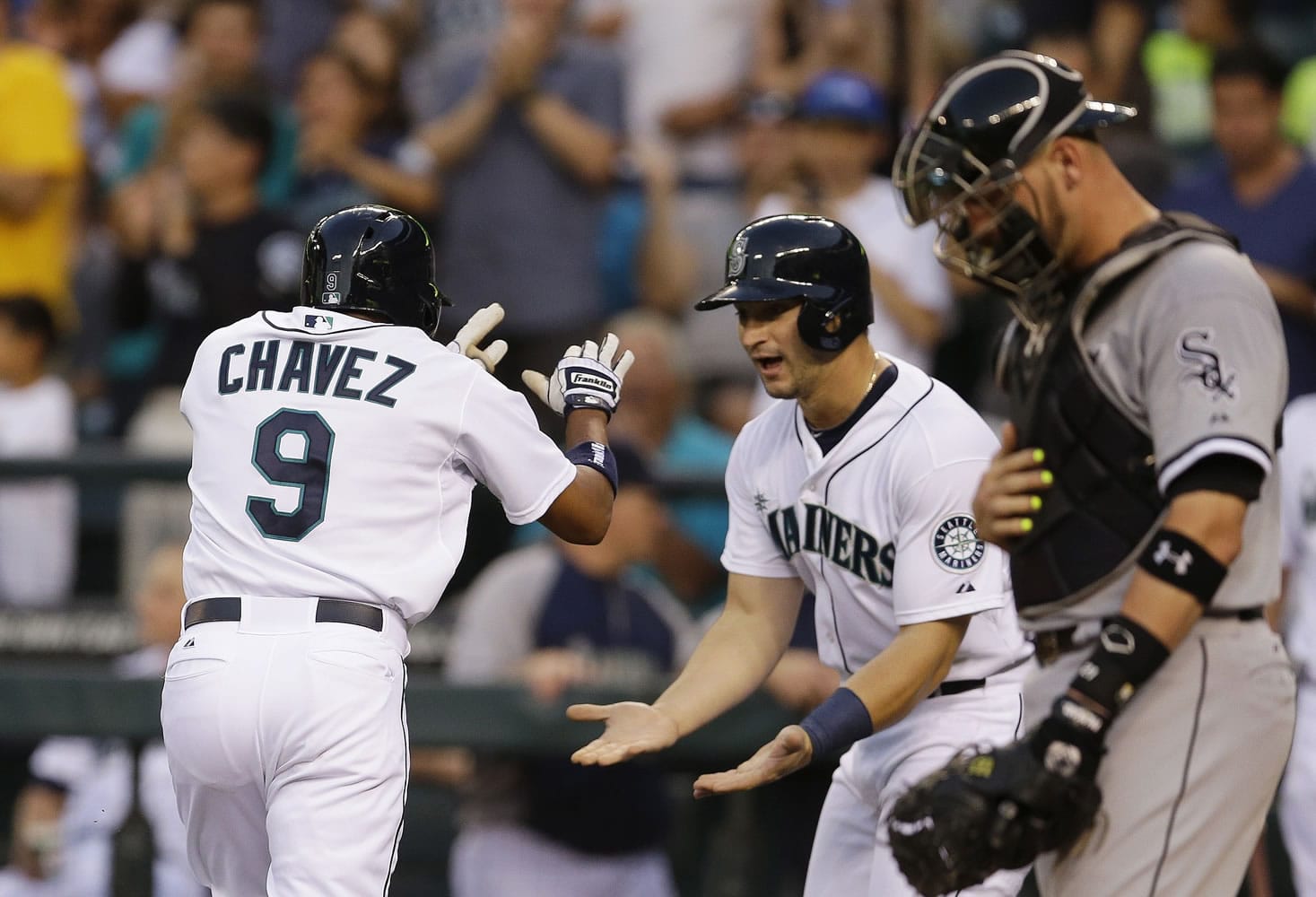 Seattle Mariners' Endy Chavez (9) is greeted at the plate by Mike Zunino, center, as Chicago White Sox catcher Tyler Flowers watches at right, after Chavez hit a two-run home run in the fourth inning of a baseball game, Thursday, Aug. 7, 2014, in Seattle. (AP Photo/Ted S.