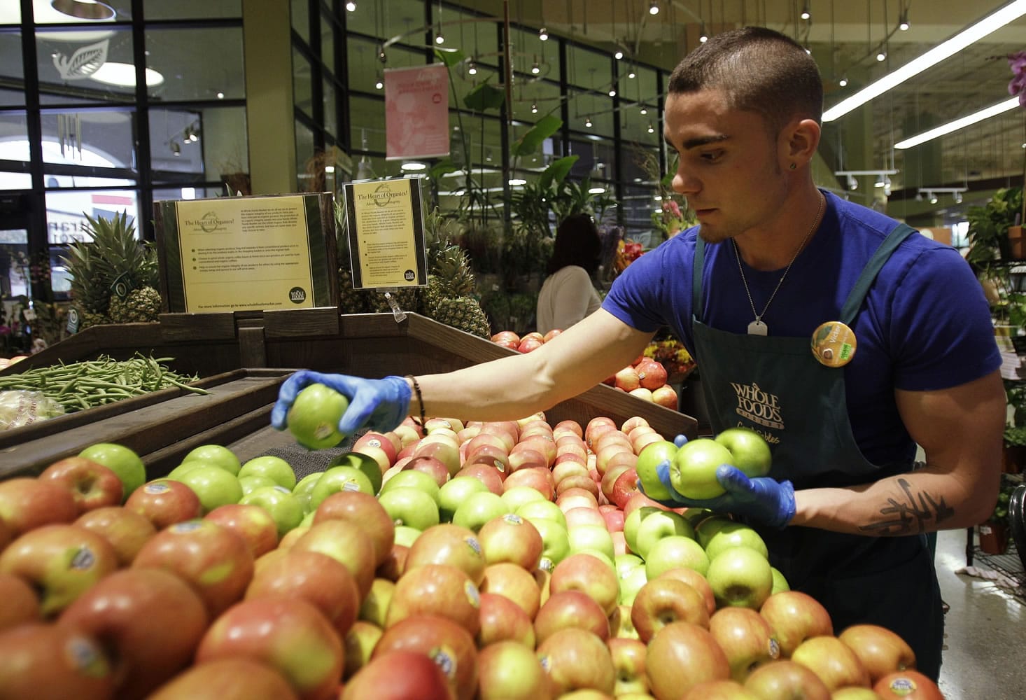Victor Hernandez stocks apples in the produce section at Whole Foods in Coral Gables, Fla.