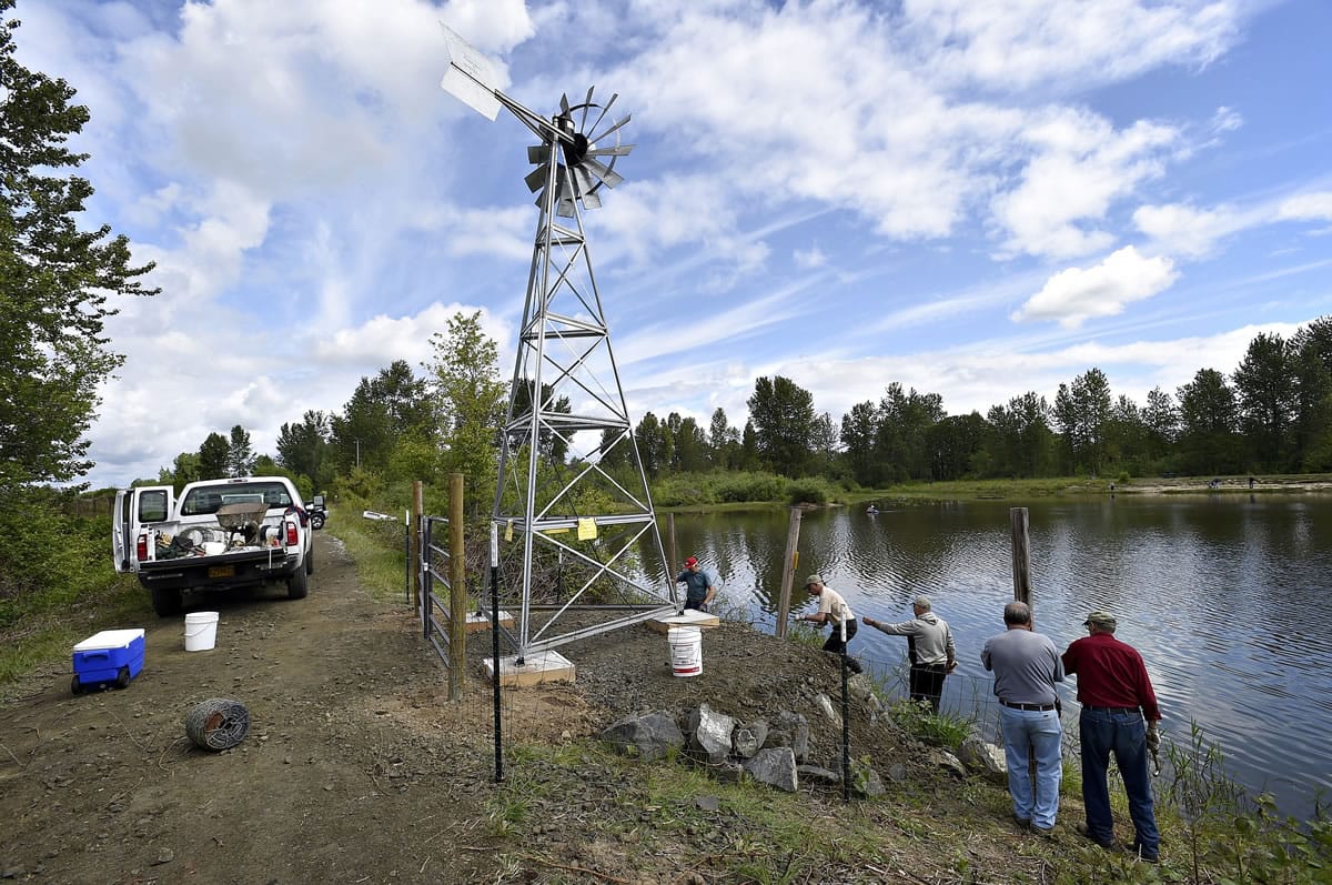 Members of the Steelheaders install barbed wire May 7 around the new windmill at the EE Wilson pond in Benton County, Ore.