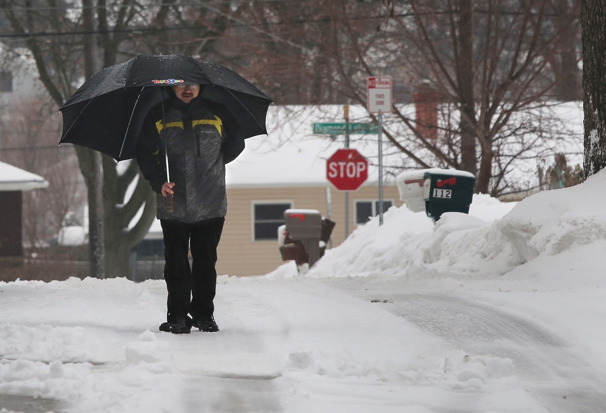Mundelein, Ill., resident Ramon Marcos walks along Elm Avenue as an icy drizzle falls after early morning snow turned to rain Tuesday in Mundelein, Ill.