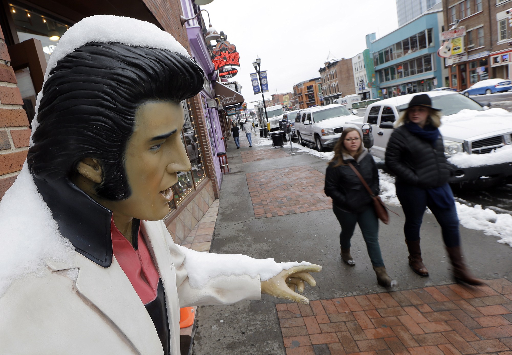 Snow covers a statue of Elvis Presley in front of a bar Thursday in Nashville, Tenn.