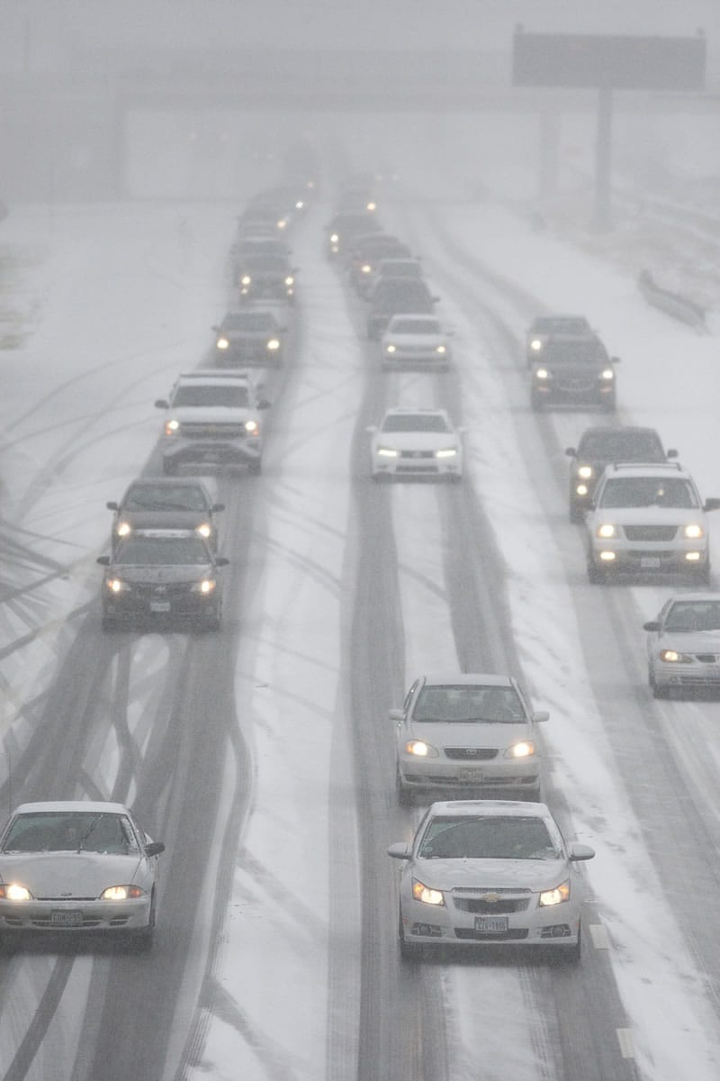 Vehicles travel along Interstate 30 as snow falls Friday in Arlington, Texas.