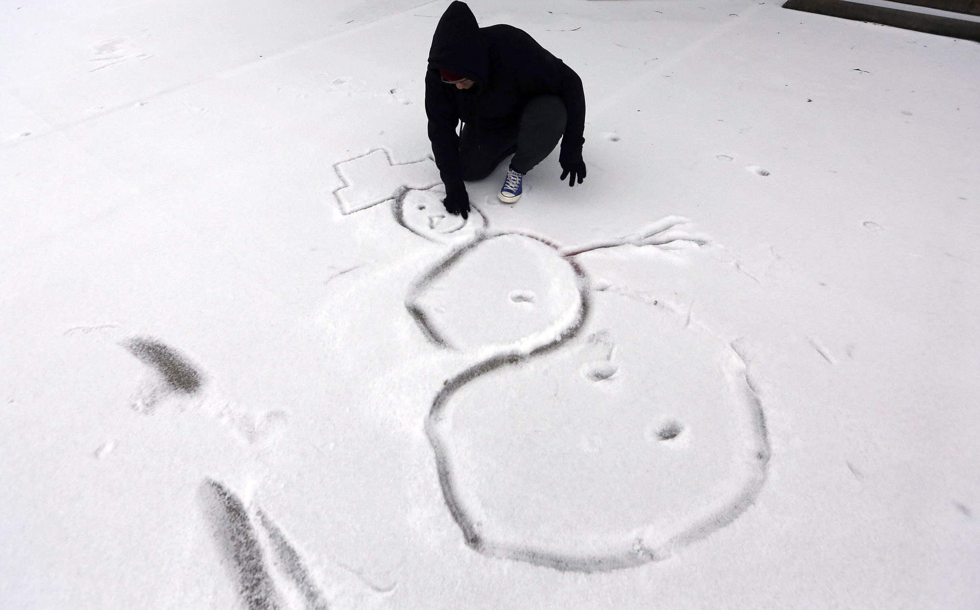 High school freshman Selena Perez, 16, draws a snowman on the ground Monday in Richardson, Texas.