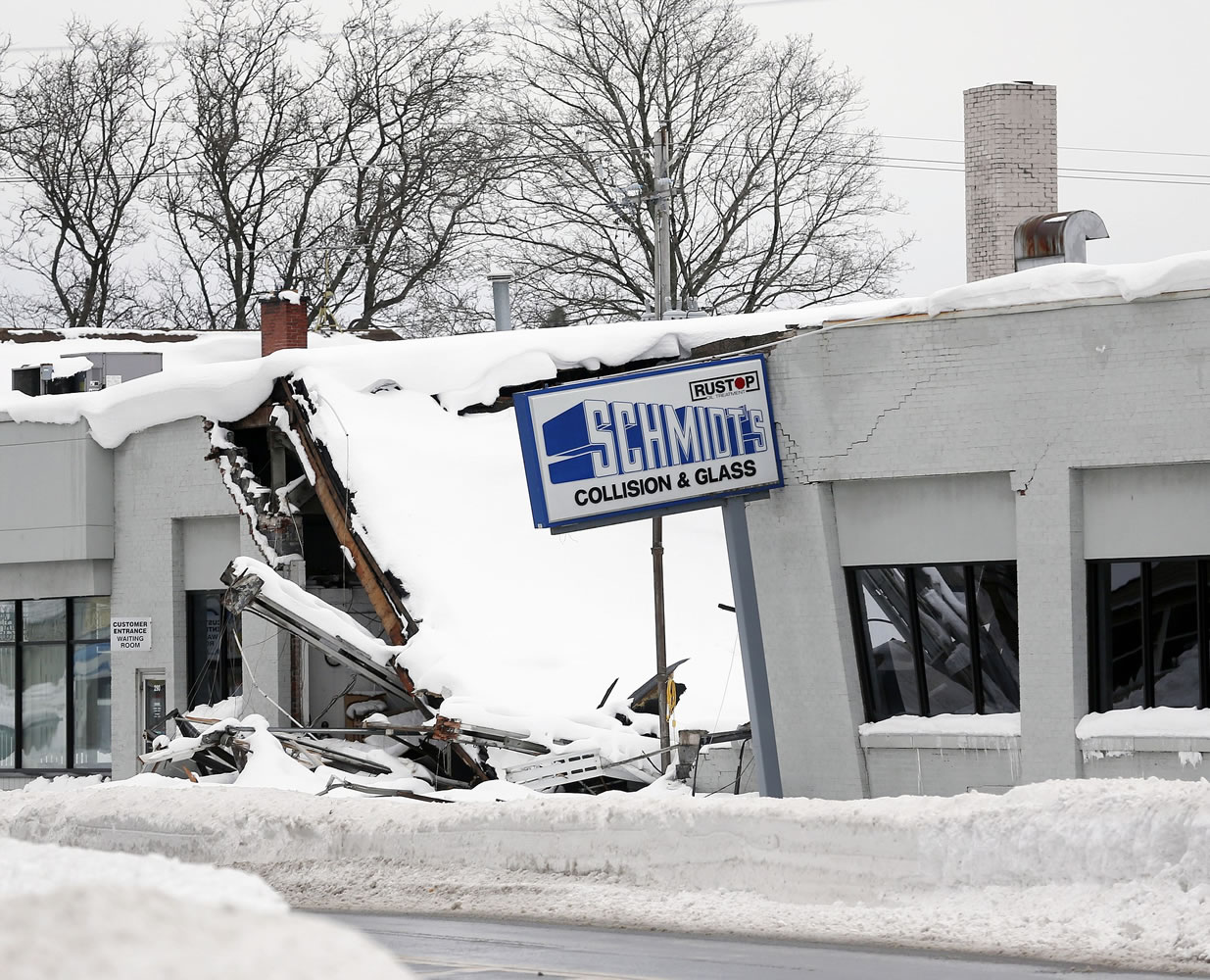 The roof at Schmidt's Collision and Glass in Hamburg, N.Y., shown Saturday, collapsed after taking on heavy snow during this week's lake-effect snowstorms.