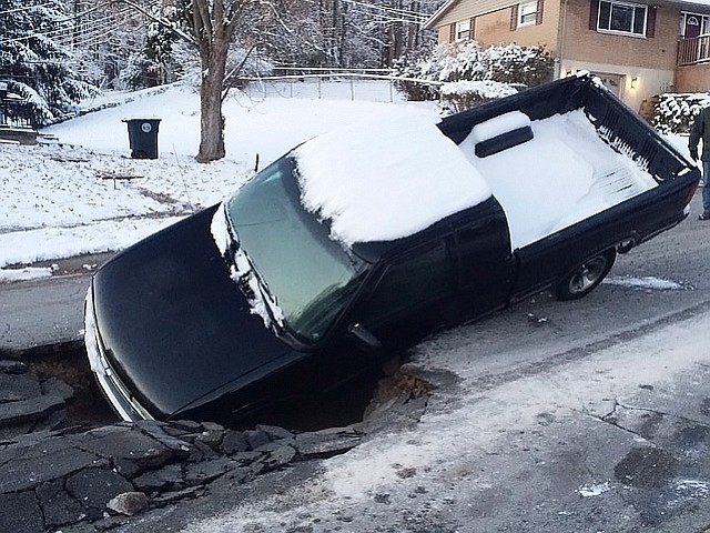 A pickup truck is stuck inside a collapsed road on Tuesday in Dayton, Ohio.