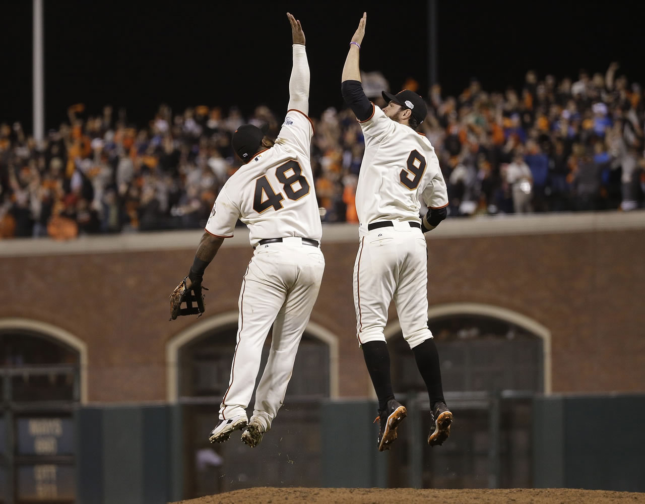 San Francisco Giants Pablo Sandoval, left, leaps up to high five Brandon Belt after defeating the Kansas City Royals 11-4 in Game 4 of the World Series on Saturday, Oct. 25, 2014, in San Francisco.