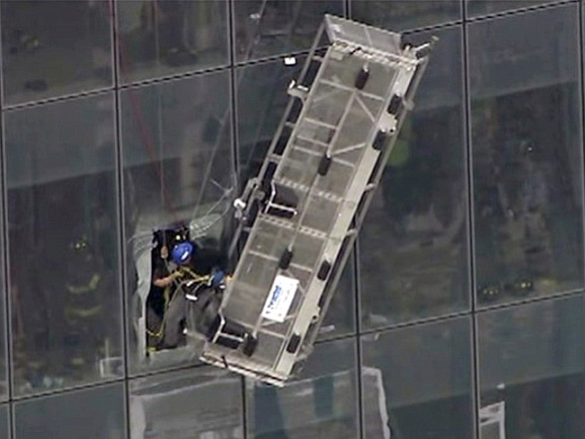 New York City firefighters remove the second of two window washers from their disabled scaffold as it dangled 69 stories up the side of 1 World Trade Center on Wednesday in New York.