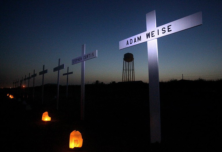 Light from a flashlight shines on a cross for Adam Weise, a floorhand who died in the Deepwater Horizon oil rig explosion, during a vigil to mark the first anniversary of the BP PLC oil spill on a beach in Grand Isle, La., on Wednesday.