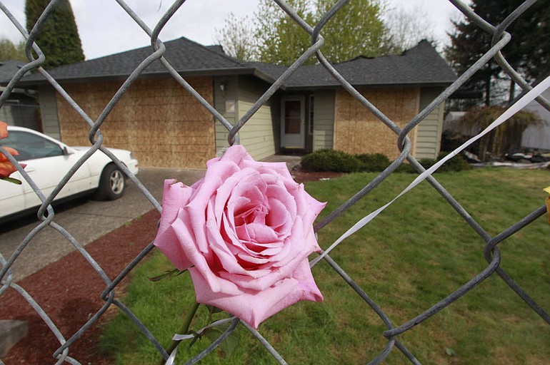 A rose hangs from a fence in front of a house April 27 where six people were killed three days earlier in a house fire, in Vancouver.