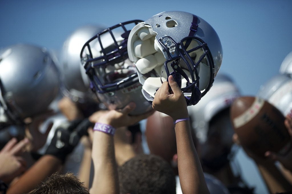 Heritage High School football players raise their helmets after a practice in 2012.