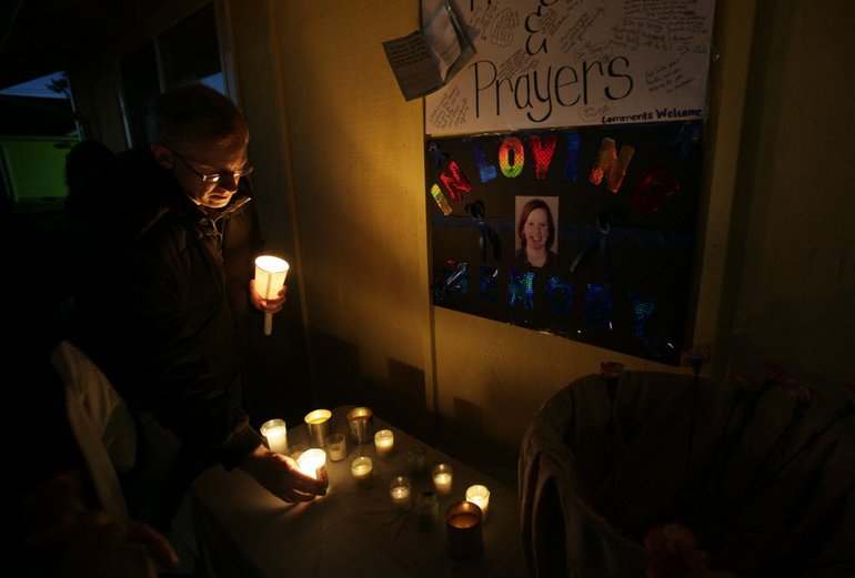 Peter Kritsch, the brother of slain park ranger Margaret Anderson, pictured on the poster at right, lights a candle in memory of his sister during an evening vigil for Anderson on Sunday in Eatonville, Wash. Anderson was killed by a gunman on Jan. 1 during a traffic stop where she worked at Mount Rainier National Park. Clark County Sheriff's Office Sgt.
